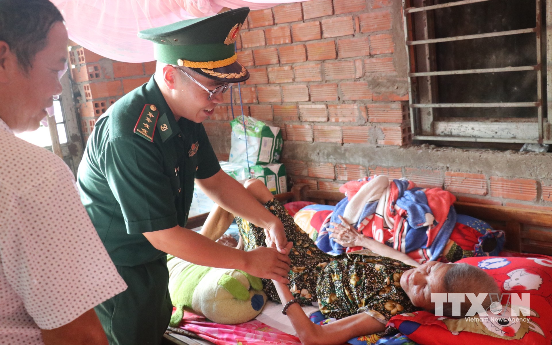 Đại úy Phạm Việt Tiến ân cần thăm hỏi, động viên người cao tuổi có hoàn cảnh khó khăn, thể hiện sự sẻ chia của người lính biên phòng với nhân dân nơi biên giới. (Ảnh: Bùi Giang/TTXVN)